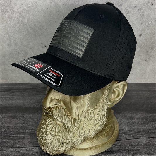 Black cap with patches on a mannequin head against a concrete wall.