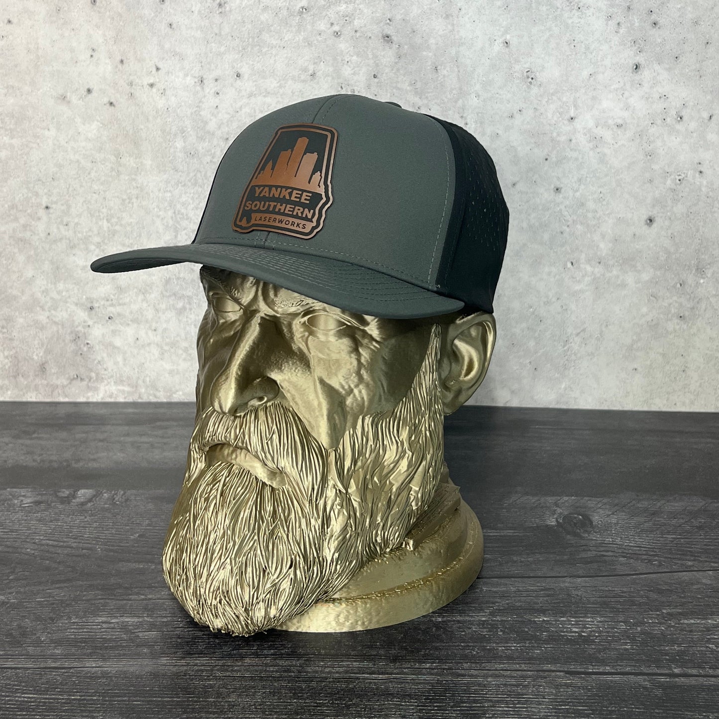 Yankee Southern Laserworks 5 panel hat with walnut colored branded patch on a gold statue.