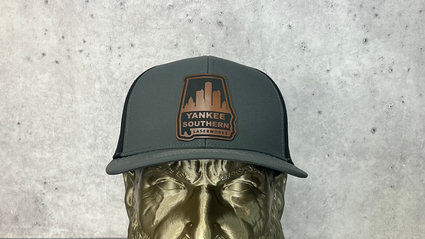 Yankee Southern Laserworks 6 panel hat with walnut colored branded patch on a gold statue.