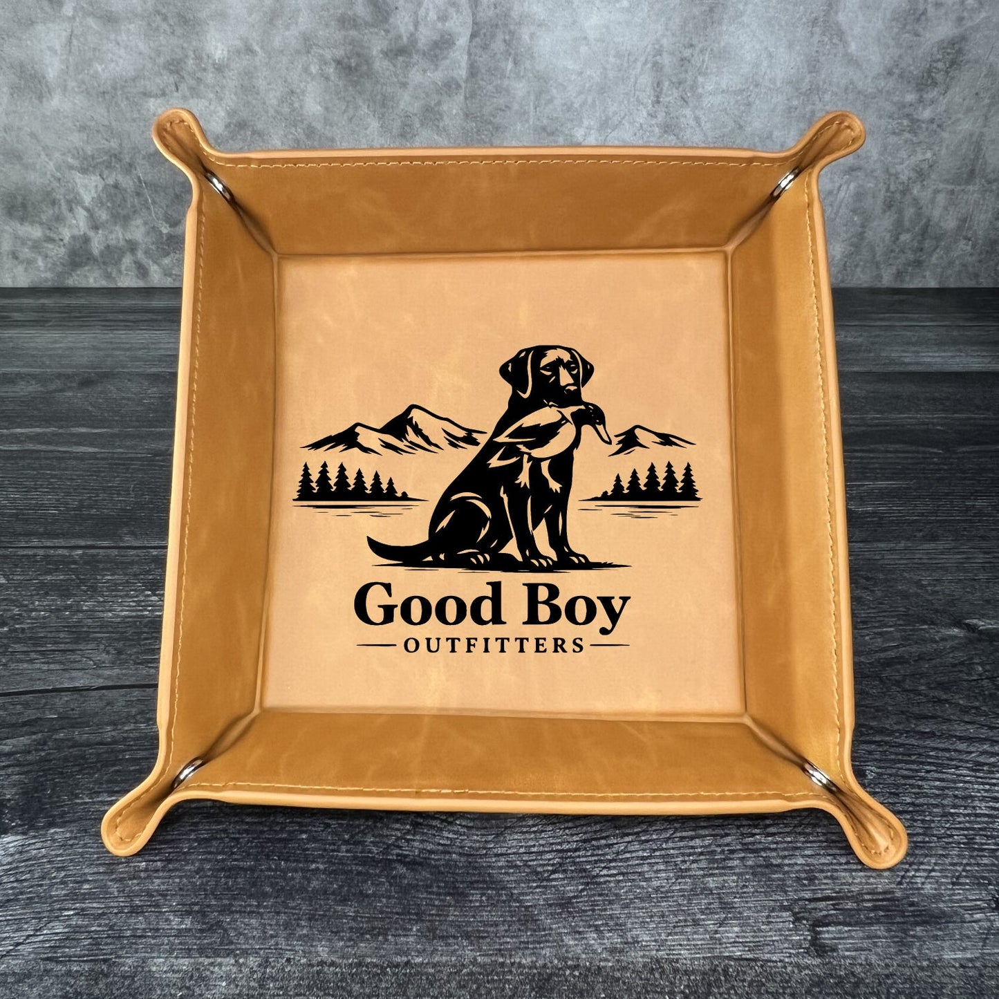 Brown leather tray with 'Good Boy Outfitters' logo on a gray background
