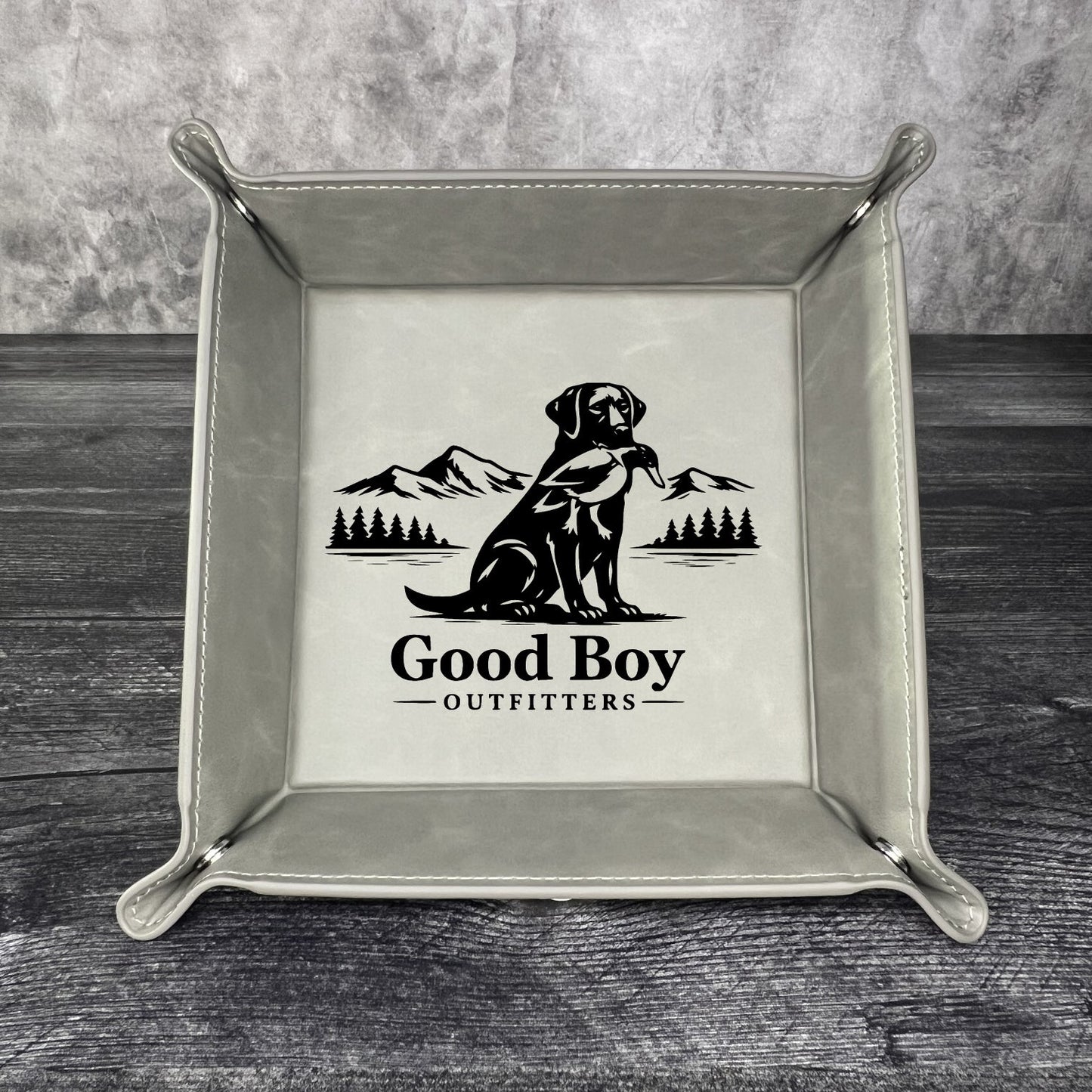 Grey valet tray with 'Good Boy Outfitters' logo on a wooden surface