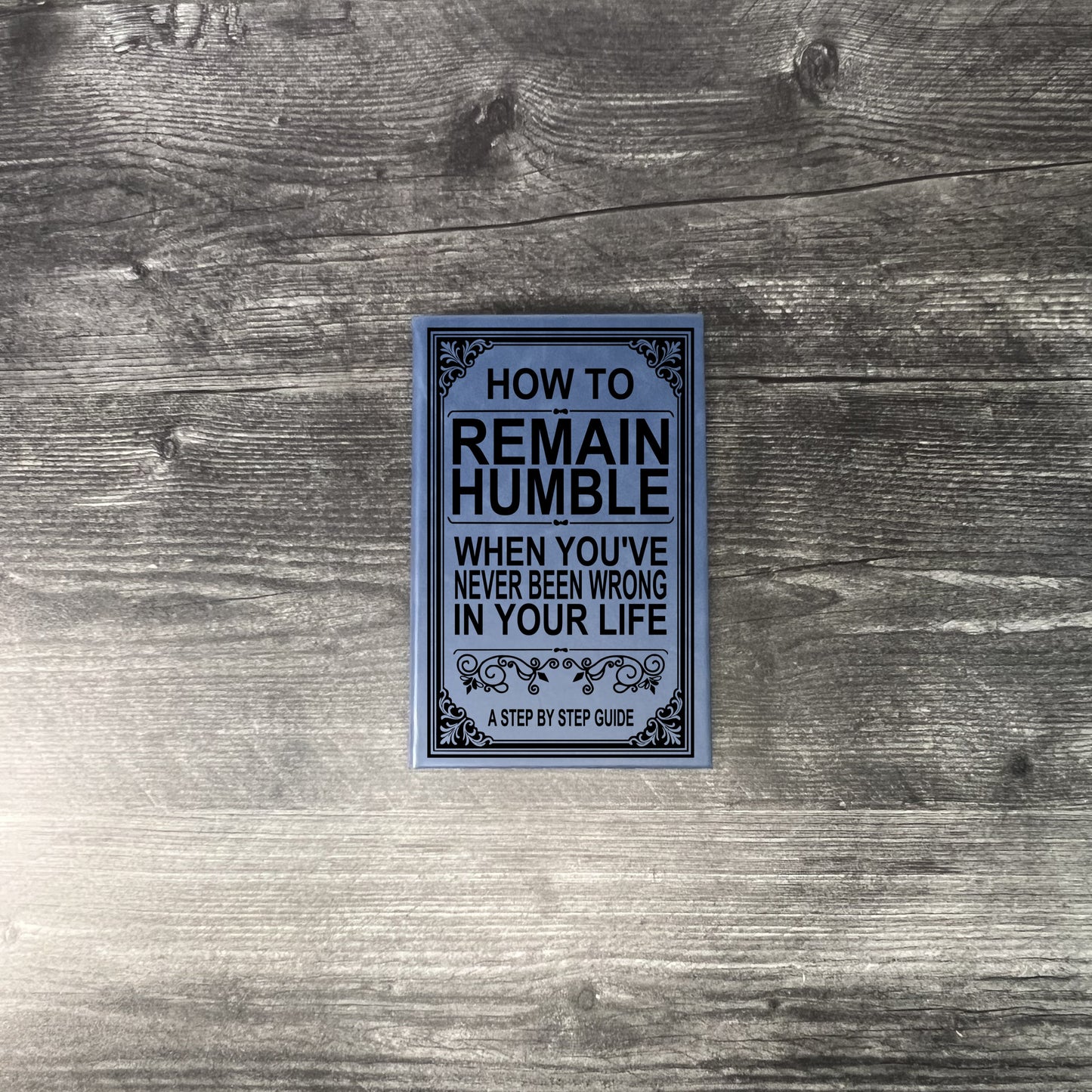 Book titled 'How to Remain Humble When You've Never Been Wrong in Your Life' on a wooden surface.