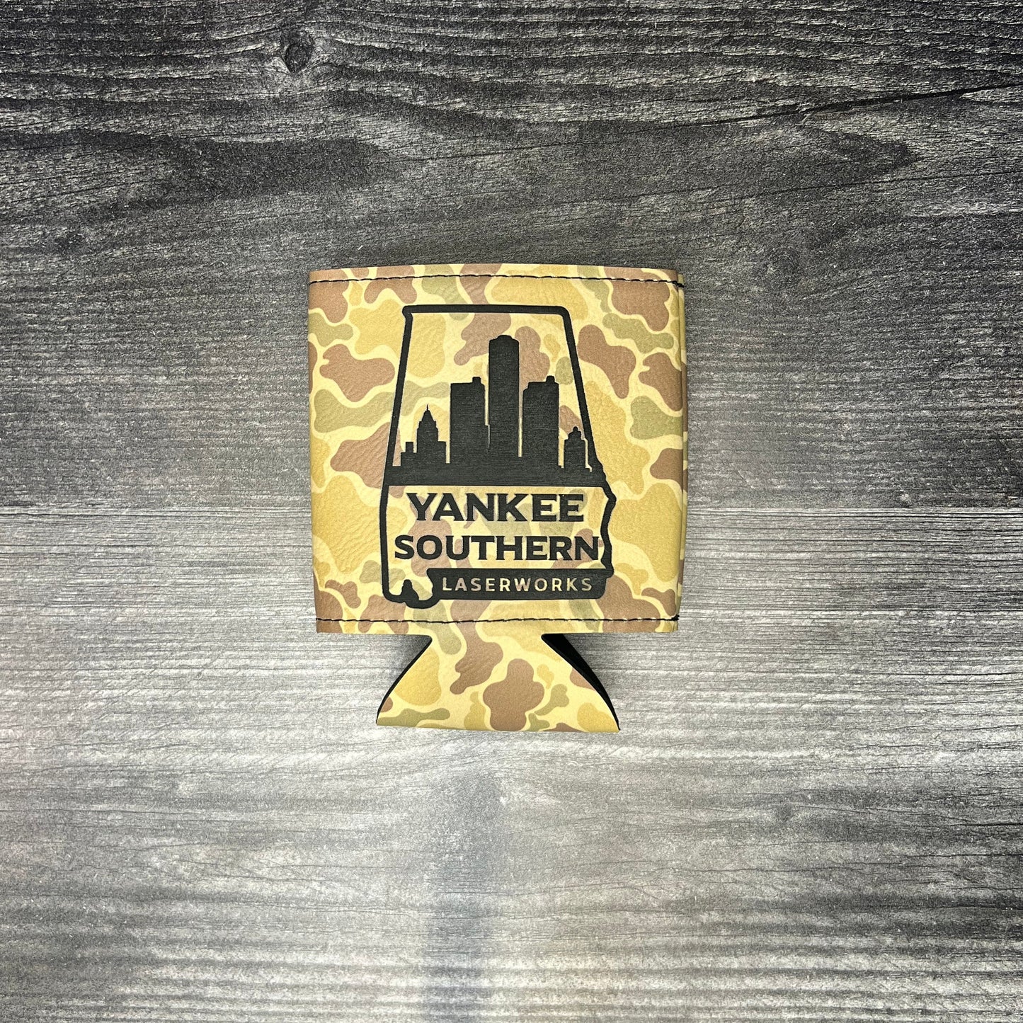 Camo-patterned can cooler with 'Yankee Southern' logo on a wooden surface