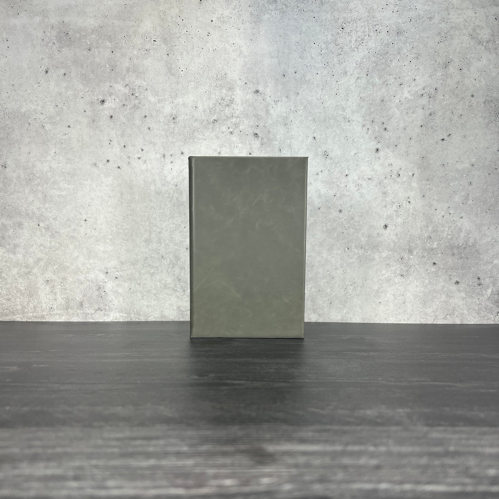 Flint leatherette journal on a wooden floor with a concrete wall