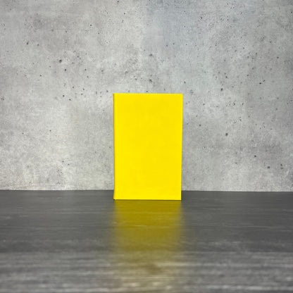 Yellow leatherette journal on a wooden floor with a concrete wall