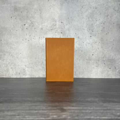 Raw leatherette journal on a wooden floor with a concrete wall