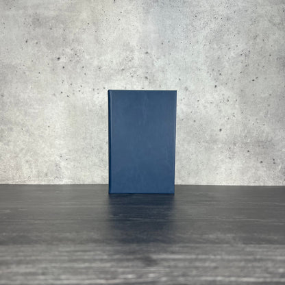 Indigo leatherette journal on a wooden floor with a concrete wall