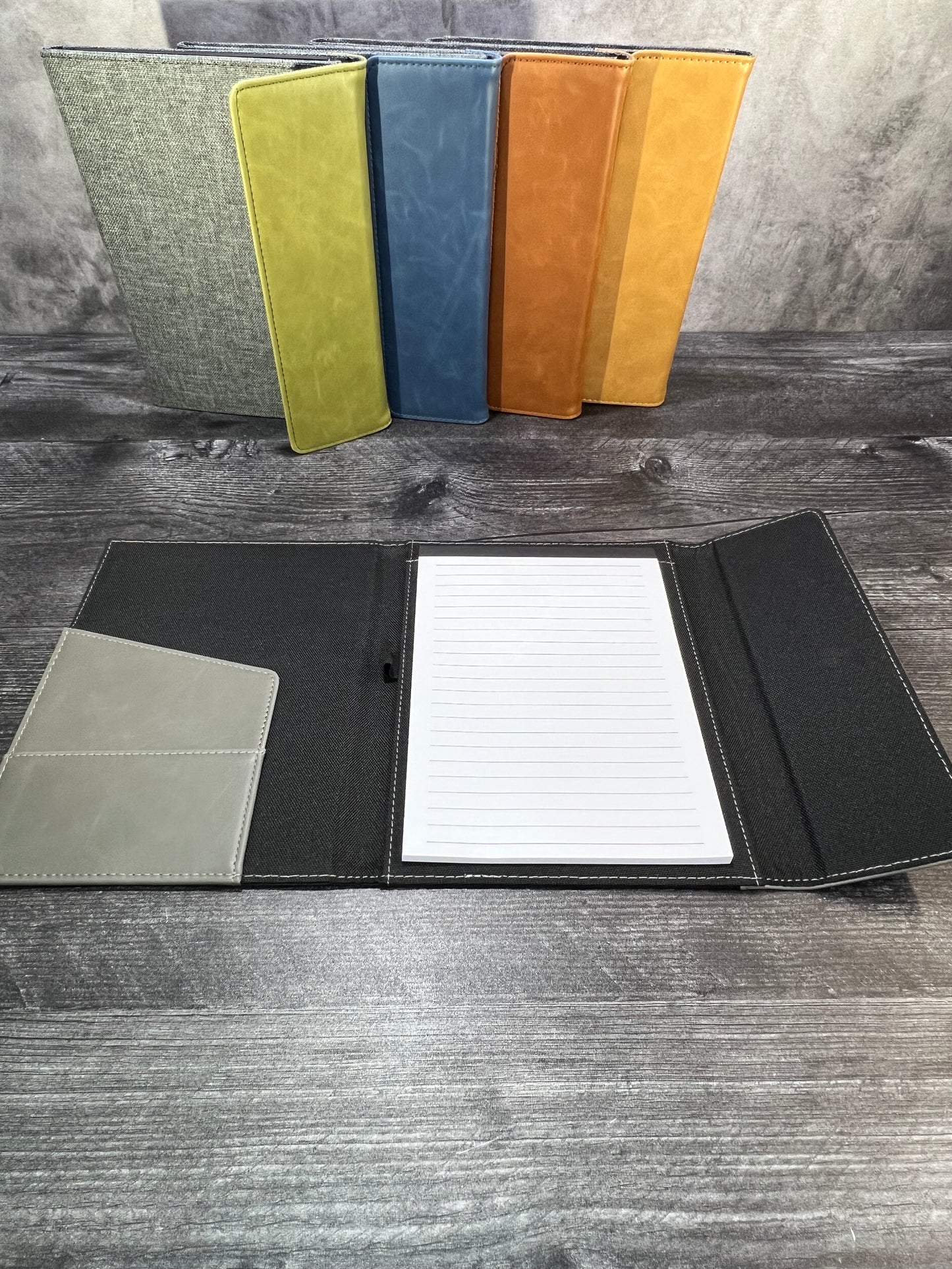 Set of color swatches and a black leather-bound notebook with lined paper on a wooden surface.
