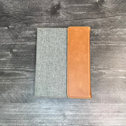 Gray fabric pouch with a brown leather patch on a wooden surface